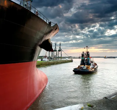Tugboat assisting a vessel alongside at dusk